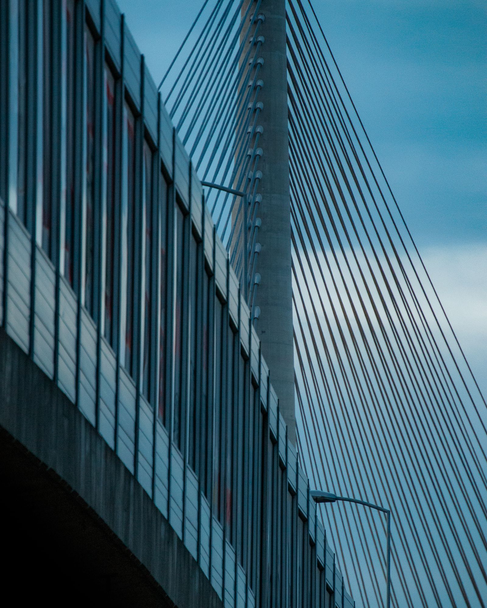 Cables and glass barrier of the Ada Bridge in Belgrade against a teal sky